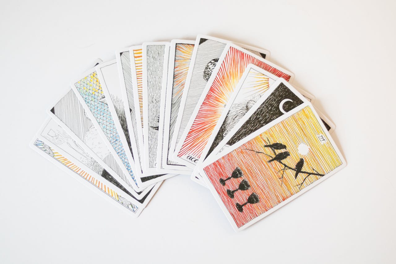 A collection of artistic tarot cards spread out on a white background.