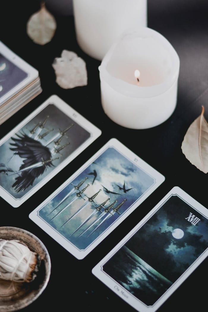 A close-up of mystical tarot cards and candles on a black surface, perfect for spiritual themes.